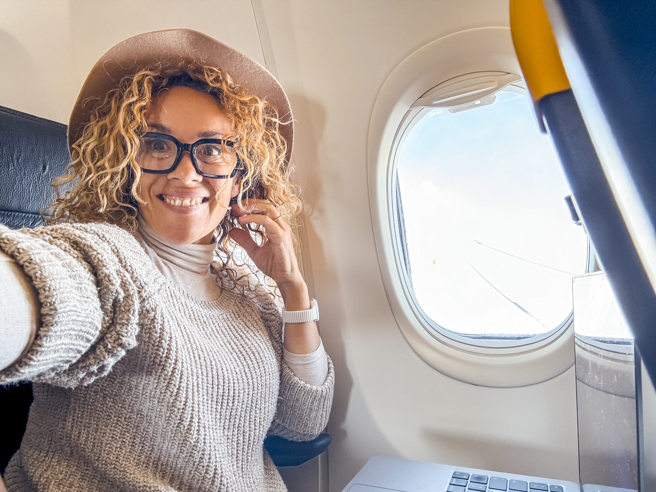 45year old blonde woman wearing glasses sitting on an airplane s